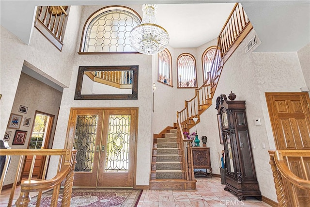 foyer featuring french doors, a notable chandelier, and a high ceiling