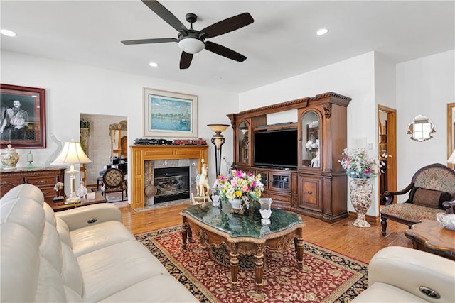 living room with light wood-type flooring, ceiling fan, and a fireplace