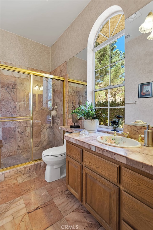 bathroom featuring vanity, a shower with shower door, and toilet