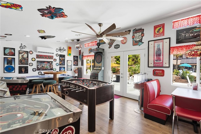 playroom featuring ceiling fan, hardwood / wood-style flooring, french doors, and a wall mounted AC