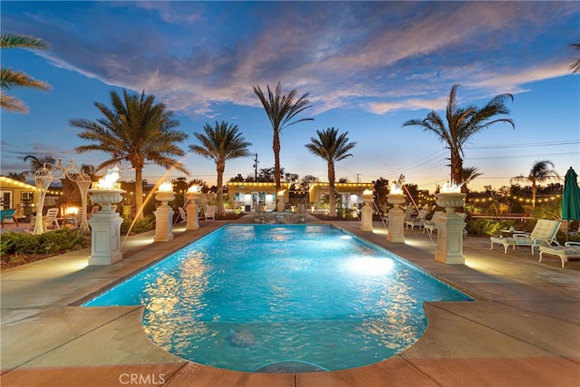 pool at dusk featuring a patio area