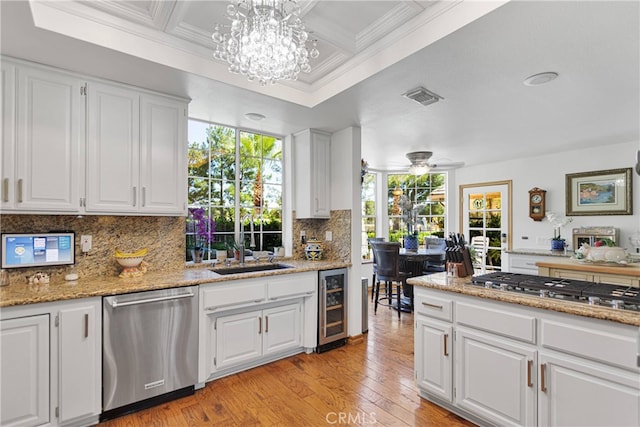 kitchen with white cabinets, wine cooler, light hardwood / wood-style flooring, appliances with stainless steel finishes, and ceiling fan with notable chandelier