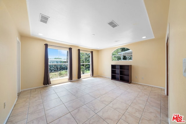 spare room featuring light tile patterned floors and a raised ceiling