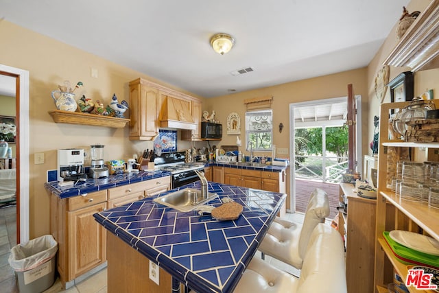 kitchen with a center island, tile countertops, custom exhaust hood, and black appliances