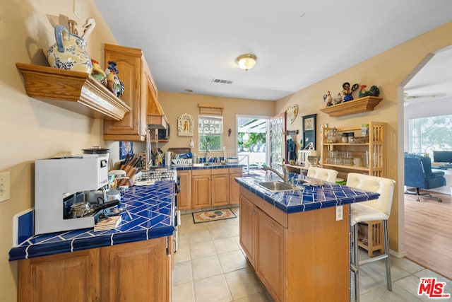 kitchen featuring tile countertops, sink, and an island with sink