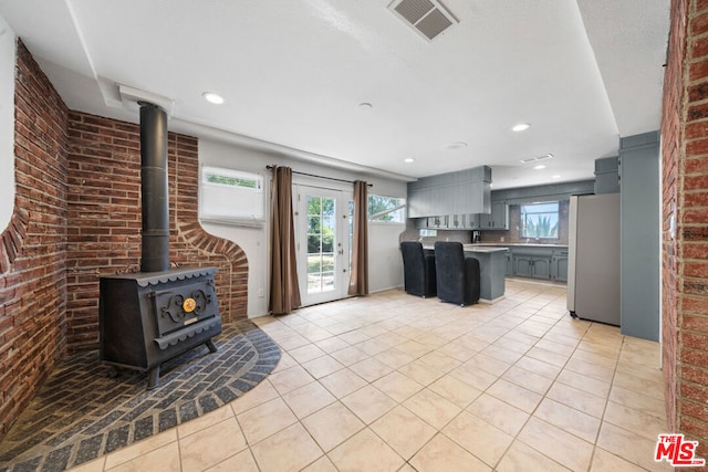 unfurnished living room with plenty of natural light, light tile patterned floors, and brick wall