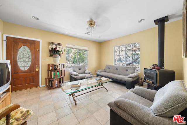 tiled living room with ceiling fan and a wood stove