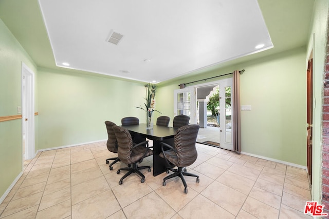 dining room with light tile patterned flooring, a raised ceiling, and french doors