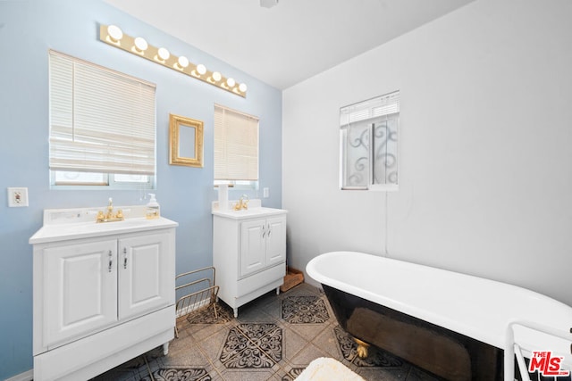 bathroom featuring tile patterned flooring, vanity, and a bath