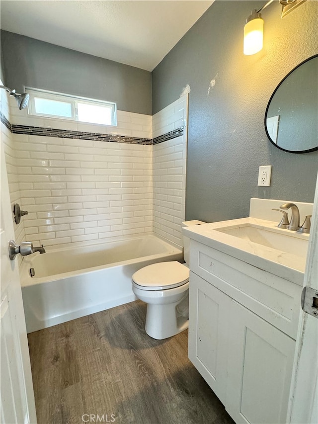 full bathroom featuring vanity, tiled shower / bath combo, toilet, and hardwood / wood-style flooring