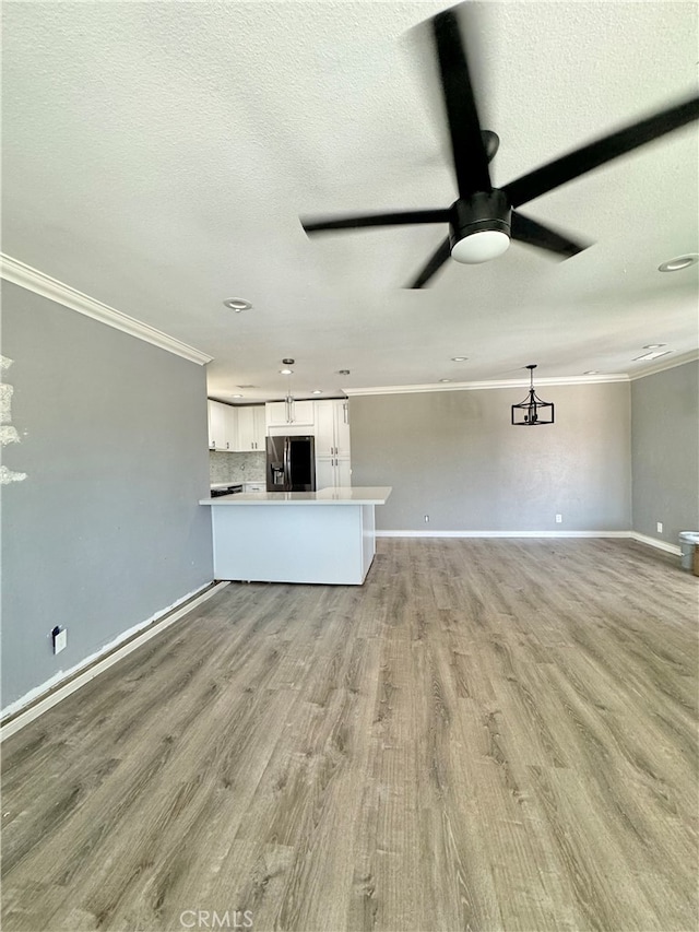 unfurnished living room with ceiling fan, a textured ceiling, light hardwood / wood-style flooring, and crown molding