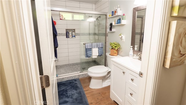 bathroom with hardwood / wood-style floors, vanity, toilet, and a shower with door