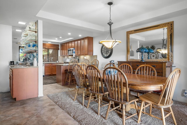 dining space featuring a raised ceiling and light tile patterned floors