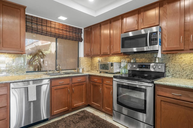 kitchen featuring light stone counters, appliances with stainless steel finishes, and tasteful backsplash