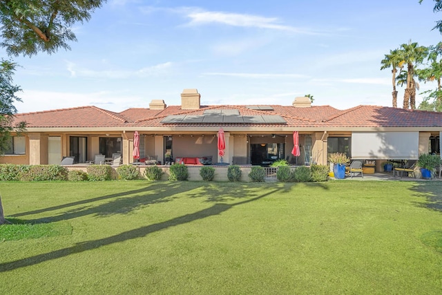 back of property with a lawn, a patio, and solar panels