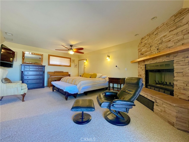 carpeted bedroom featuring a fireplace and ceiling fan