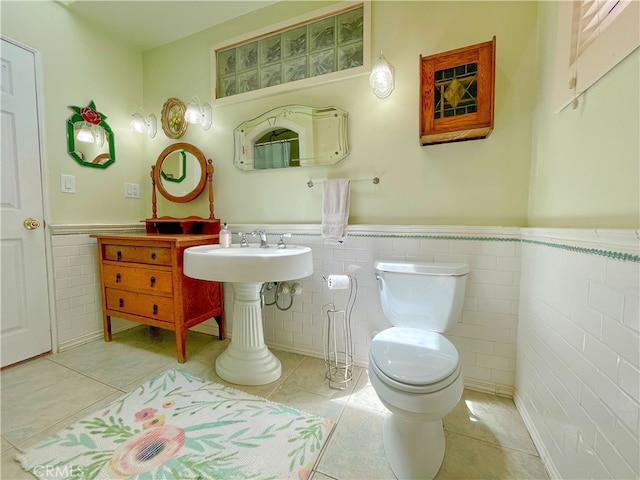 bathroom with toilet, tile patterned floors, and tile walls