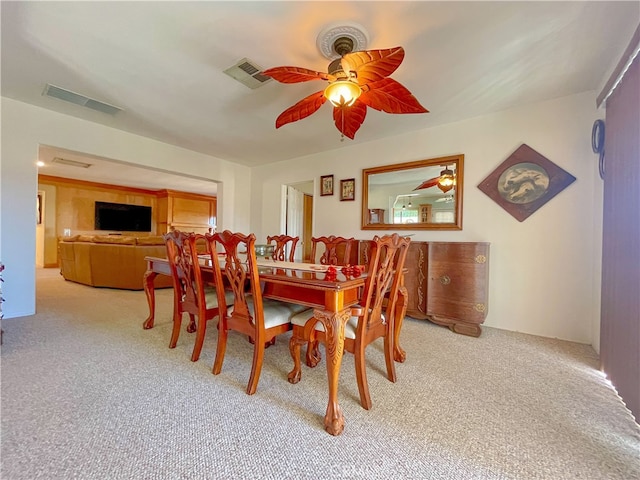 carpeted dining room with ceiling fan