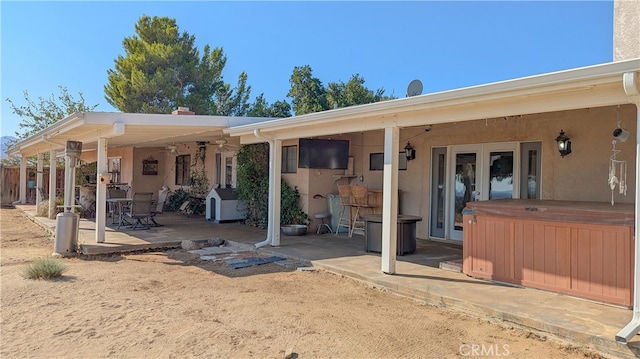 back of property with a hot tub and a patio area