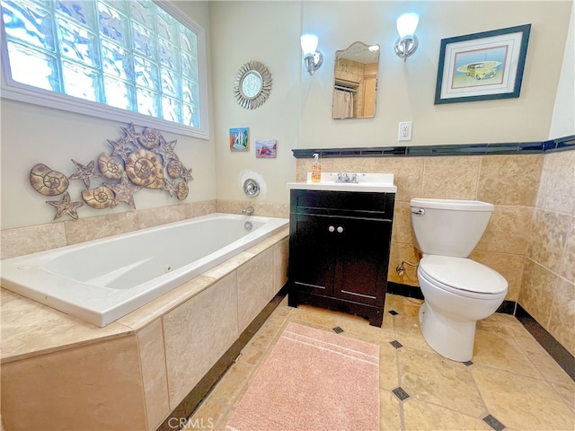 bathroom with tile patterned floors, toilet, tiled tub, vanity, and tile walls