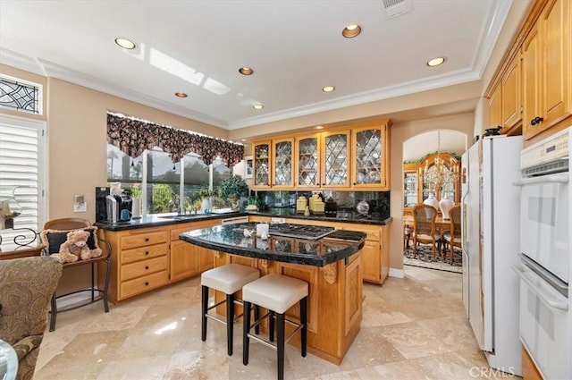 kitchen with a center island, sink, white appliances, decorative backsplash, and a breakfast bar