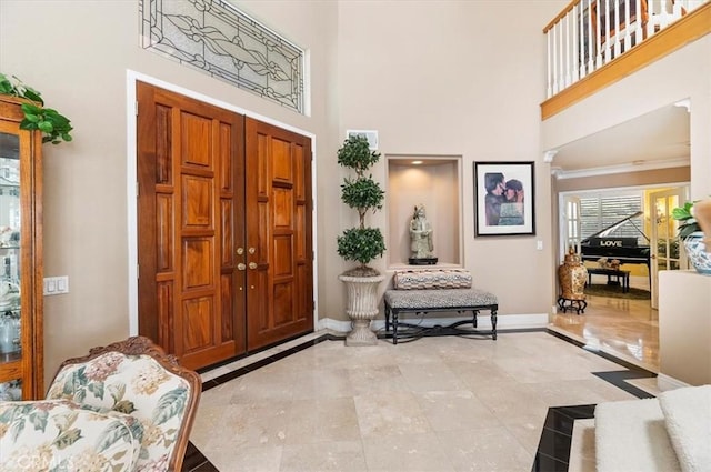 foyer entrance with a towering ceiling and ornamental molding