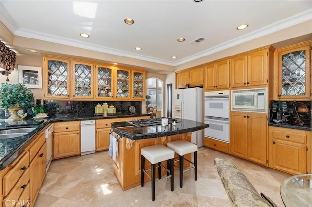 kitchen with white appliances, a kitchen bar, decorative backsplash, a kitchen island, and ornamental molding