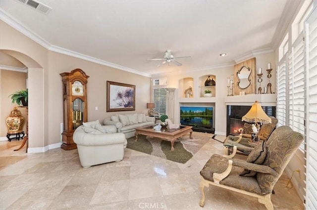 living room featuring built in features, ceiling fan, and crown molding