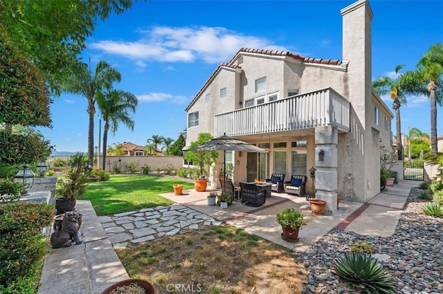 back of house featuring a lawn, a balcony, and a patio