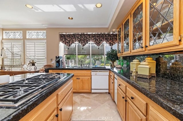 kitchen with sink, dark stone countertops, white dishwasher, stainless steel gas stovetop, and decorative backsplash