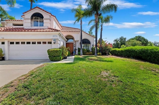 mediterranean / spanish home featuring a garage and a front yard