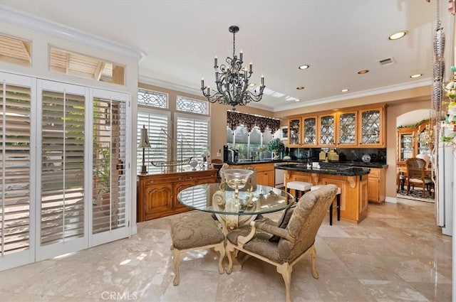 dining room featuring ornamental molding, bar, and a chandelier