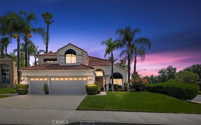 mediterranean / spanish-style home featuring a garage and a yard