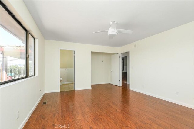 unfurnished bedroom featuring a closet, ensuite bath, ceiling fan, and hardwood / wood-style floors