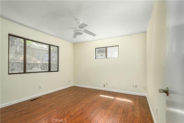 empty room with visible vents, ceiling fan, baseboards, and wood finished floors