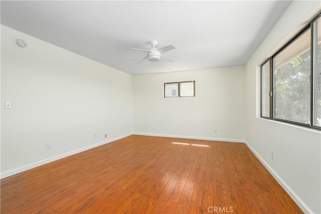 unfurnished room featuring wood finished floors, a ceiling fan, and baseboards