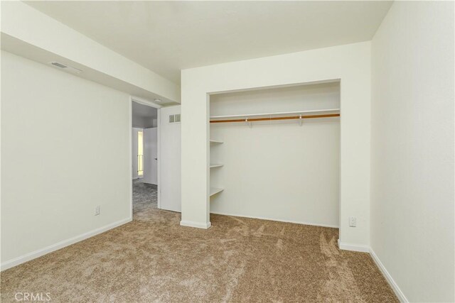 unfurnished bedroom featuring light carpet and a closet