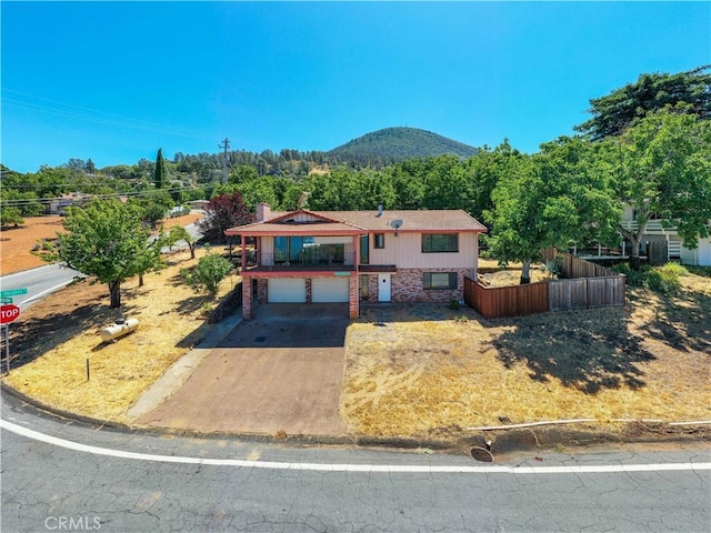 view of front of home with a mountain view, a garage, fence, concrete driveway, and a chimney