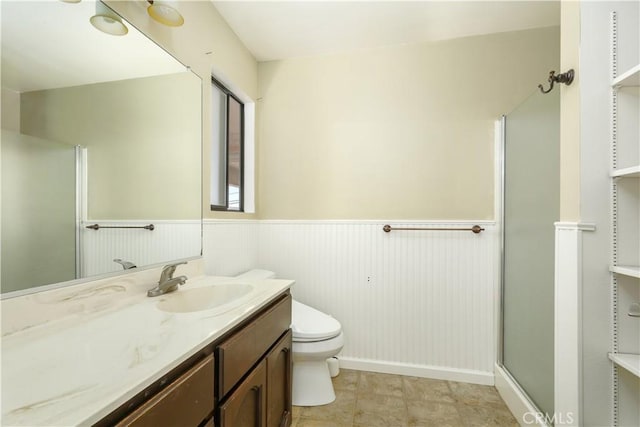 bathroom featuring toilet, wainscoting, a shower stall, and vanity