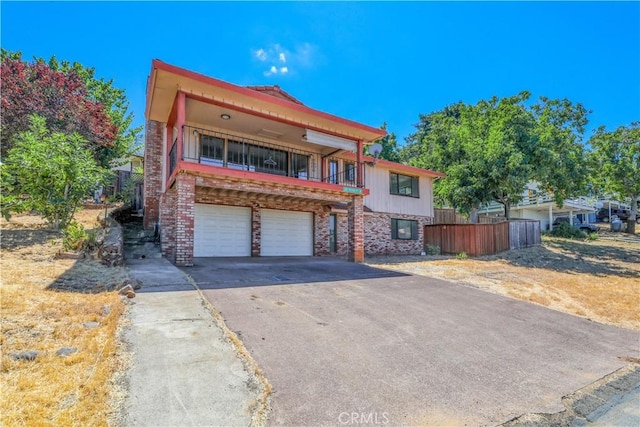 view of front facade with a garage, fence, concrete driveway, and brick siding