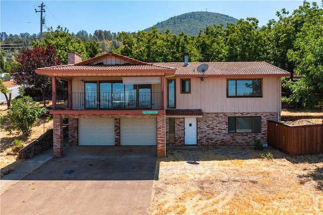 view of front of property featuring an attached garage, a mountain view, brick siding, a tile roof, and concrete driveway