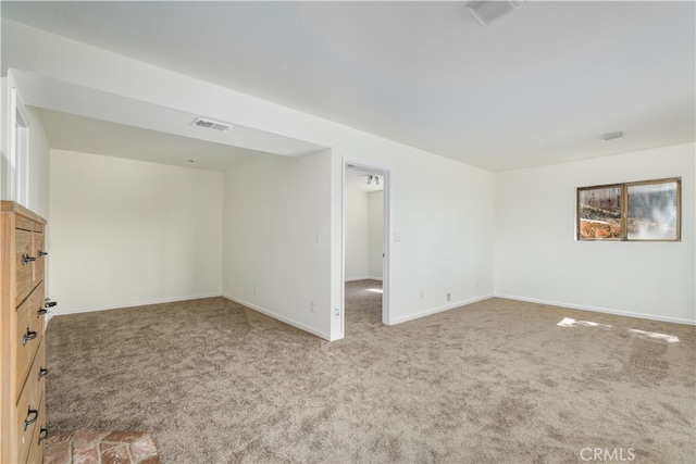 unfurnished room with carpet, visible vents, and baseboards