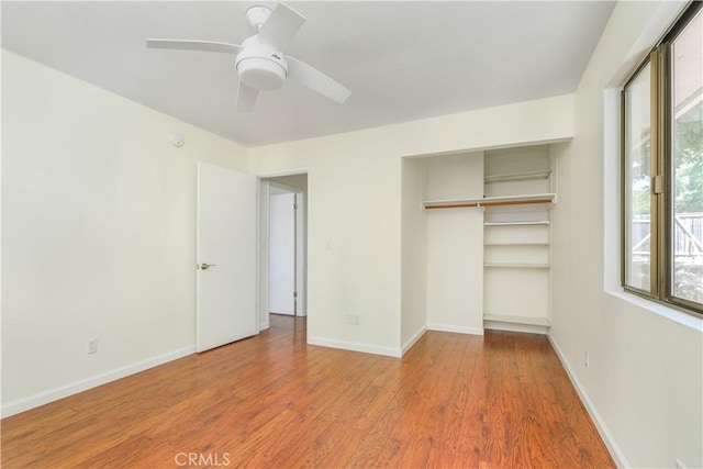 unfurnished bedroom featuring a ceiling fan, a closet, light wood-style flooring, and baseboards