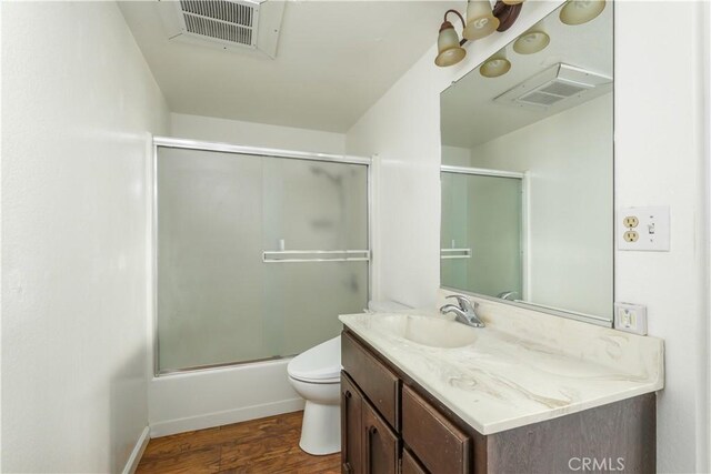 full bathroom featuring combined bath / shower with glass door, hardwood / wood-style flooring, vanity, and toilet