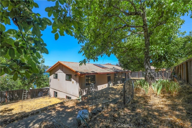 back of property featuring a fenced backyard and a tiled roof