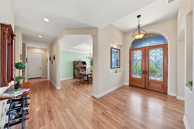 foyer entrance with a chandelier, light hardwood / wood-style flooring, and french doors