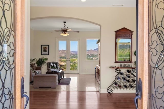 entrance foyer with wood-type flooring, french doors, ceiling fan, ornamental molding, and a mountain view