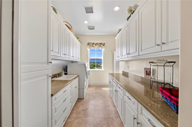 washroom featuring sink, light tile patterned floors, cabinets, and washer and dryer