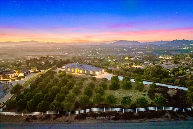 aerial view at dusk featuring a mountain view and a rural view