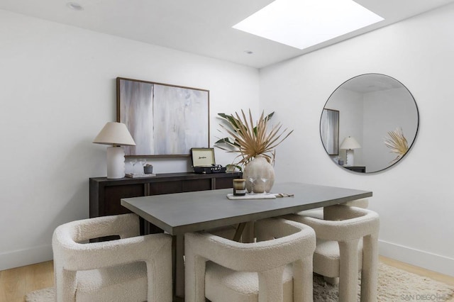 dining area with a skylight and light hardwood / wood-style floors